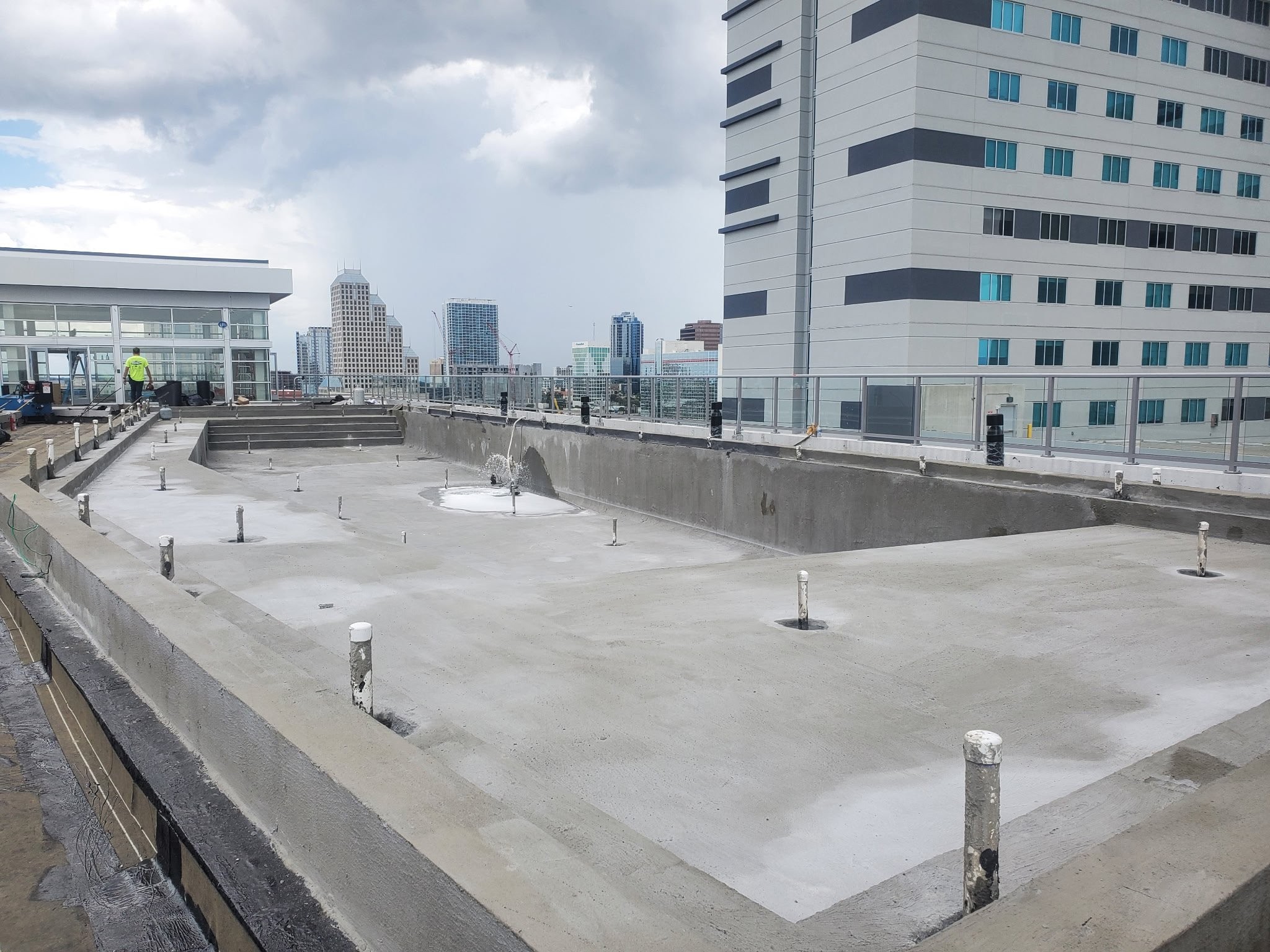 Downtown high-rise rooftop commercial pool construction with Orlando city skyline in background