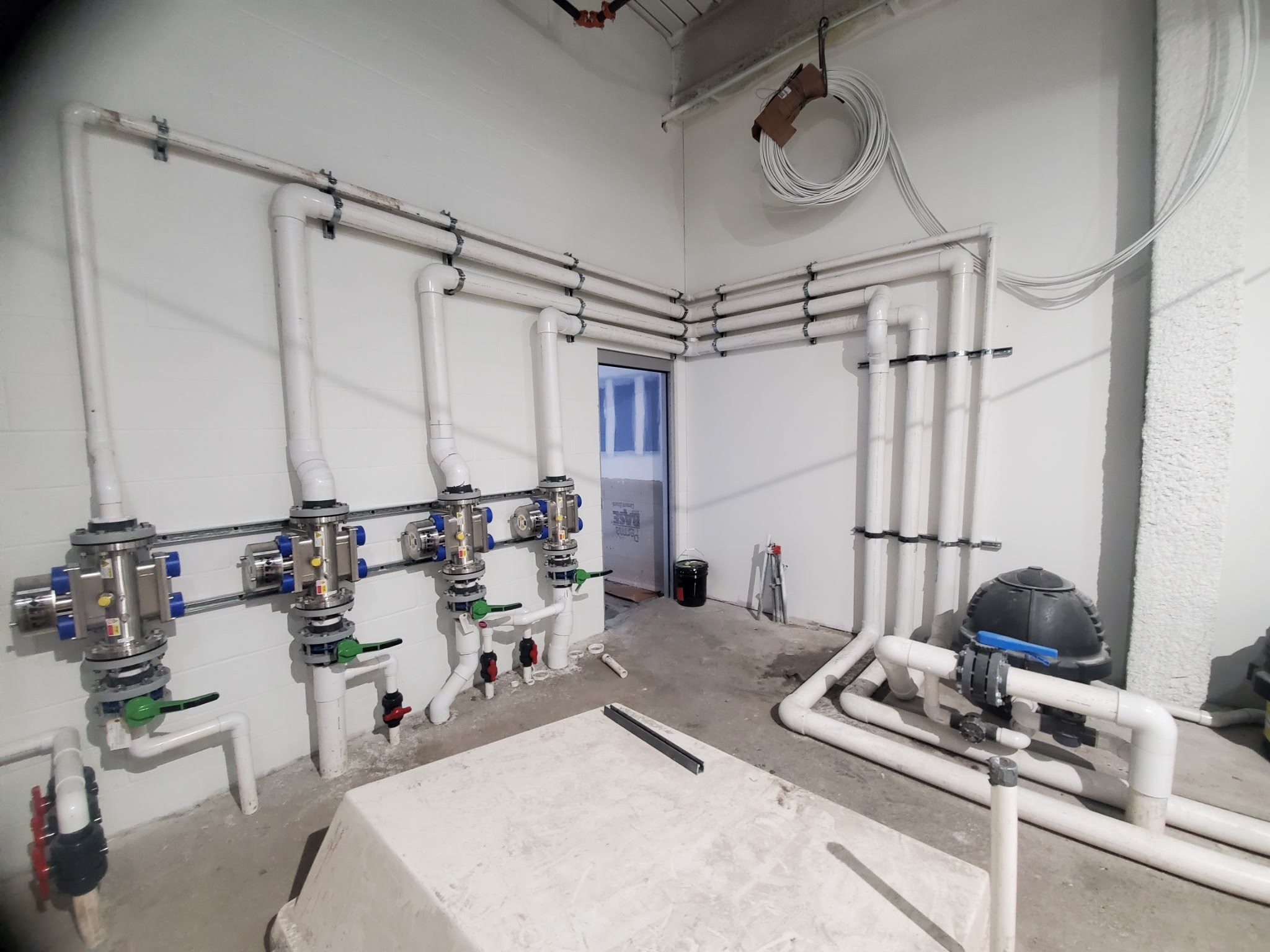 Commercial pump room with wall-mounted valve manifolds and precision plumbing