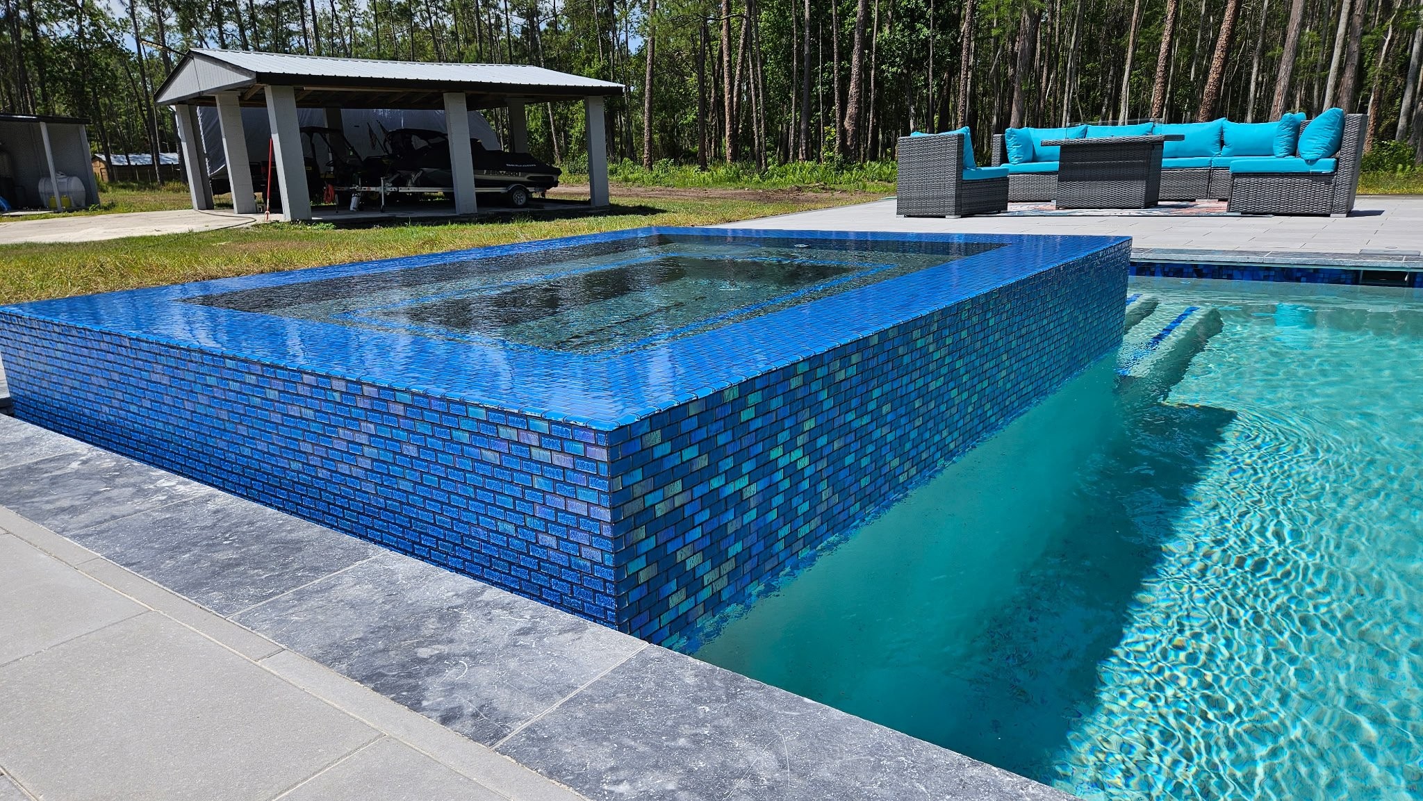 Elevated spa with iridescent blue glass tile overlooking pool