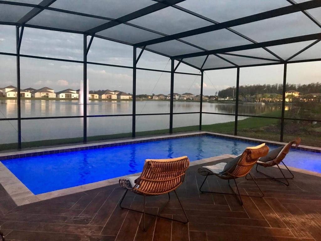 Luxury pool with panoramic lake view at dusk inside screened enclosure