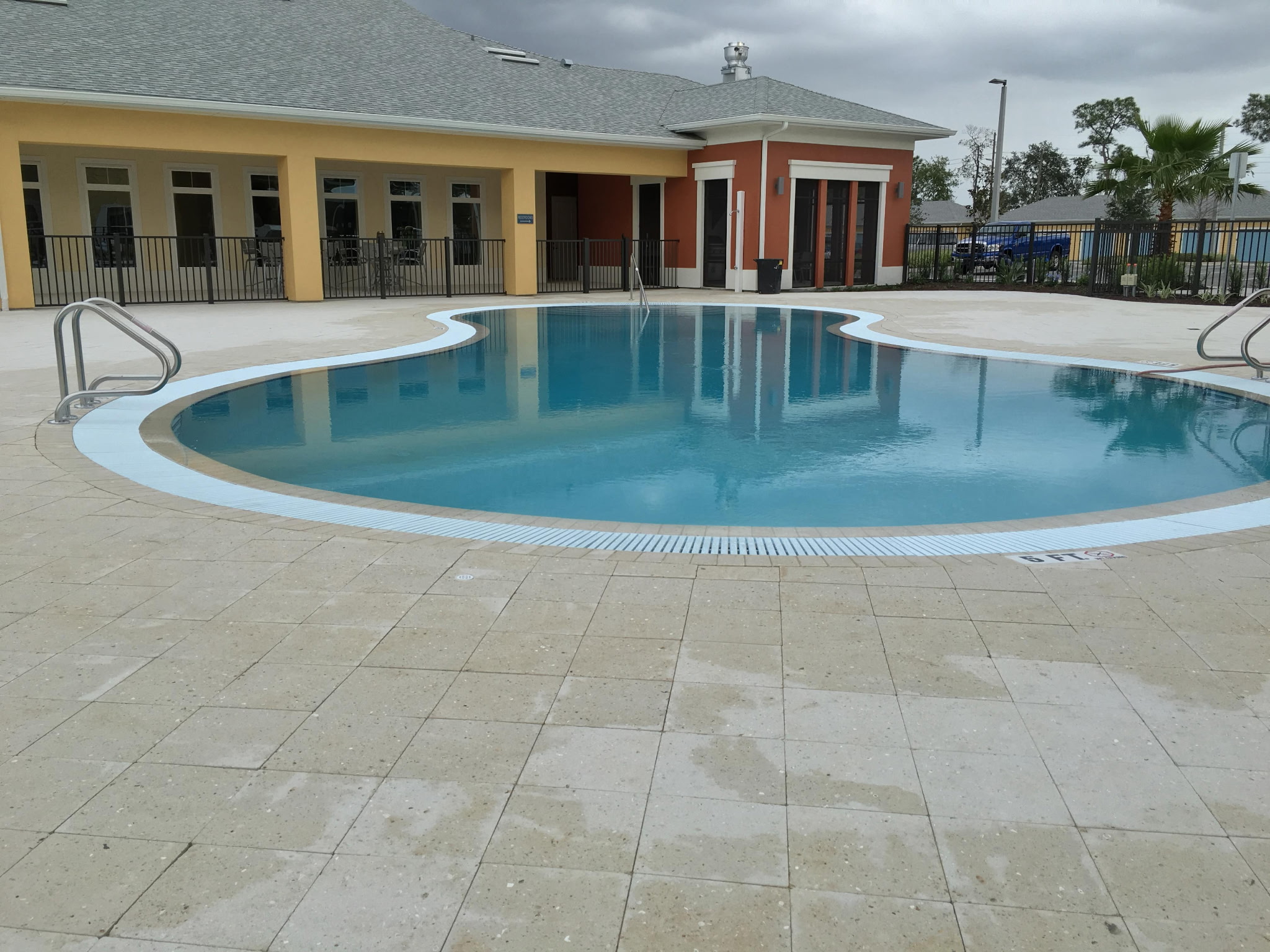 Finished commercial freeform pool with travertine deck and crystal blue water